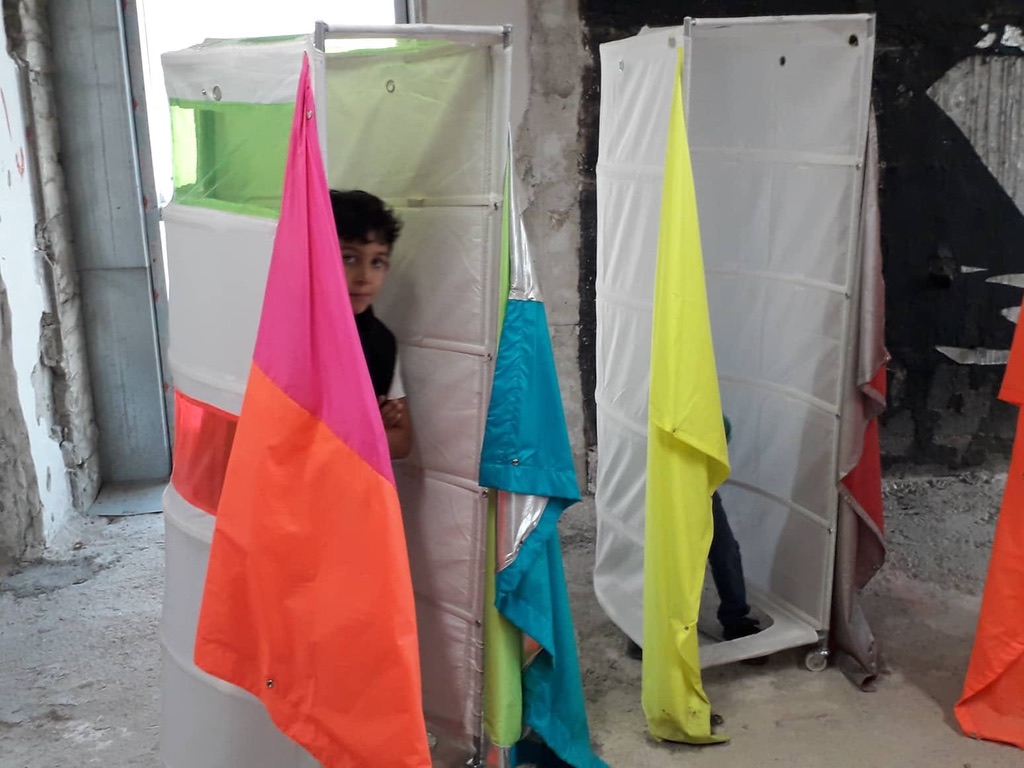 A child standing between colorful fabric-covered structures